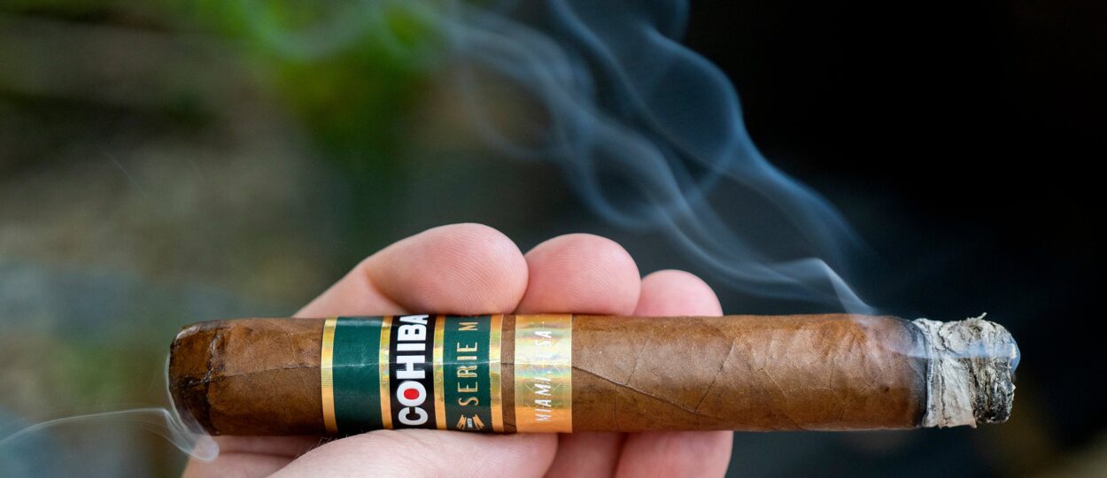 Cohiba Behike BHK 52 with red and yellow band on wooden humidor background